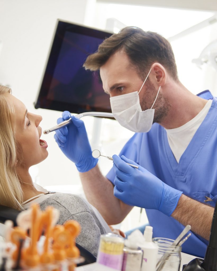 Focused dentist using dental drill and dental mirror